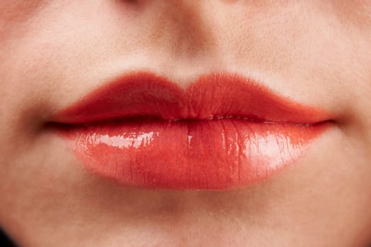 Close-up of womans lips with red glossy lipstick