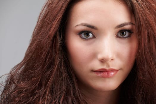 Portrait of beautiful young woman with make-up on grey background