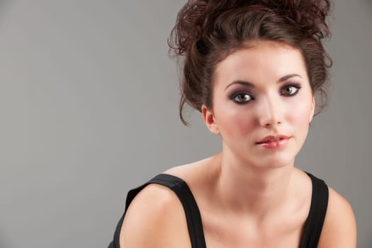 Portrait of beautiful young woman with make-up on grey background
