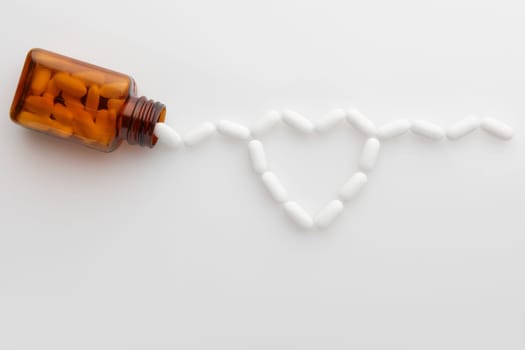 tablets coming out of bottle and forming shape of a heart