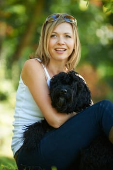 woman relaxing with black dog while on a walk in the park