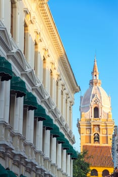 Spire of the cathedral in Cartagena, Colombia with a white historic colonial building also visible