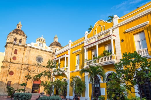 Church and yellow colonial building visible from San Pedro Claver plaza in historic Cartagena, Colombia