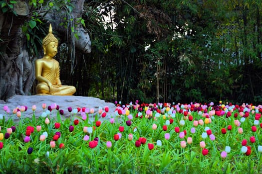Buddha meditating in a field of tulips under a bodhi tree