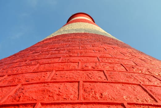 A red and white light house towers into the light blue sky