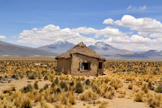 Typical Bolivian house with volcanoes in National park Sajama, Bolivia, South America.
