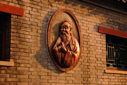 A bronze Statue of Confucius on the wall of a Confucius temple in Beijing, China