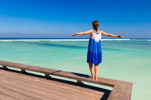 Beautiful woman walking with arms open on a beautiful tropical beach