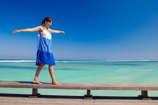Beautiful woman walking with arms open on a beautiful tropical beach