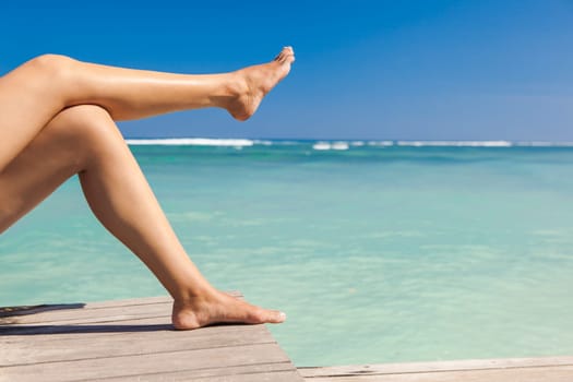 Beautiful female legs with a beautiful tropical beach as background