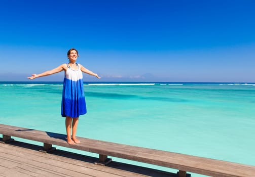 Beautiful woman walking with arms open on a beautiful tropical beach
