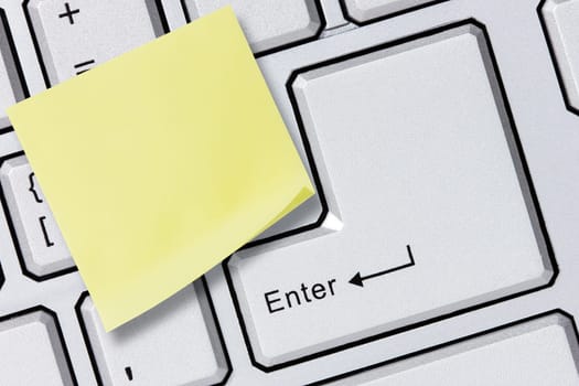 Silver computer keyboard with yellow reminder note