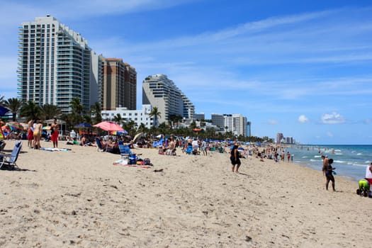 FORT LAUDERDALE, FLORIDA - APRIL 8, 2013: Long distance view of public beach filled with many people on spring break vacations, enjoying the warm sunny weather on the sand and in the Atlantic ocean.