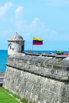 Defensive wall of Cartagena with a Colombian flag waving and several cannons visible in the old town of Cartagena, Colombia