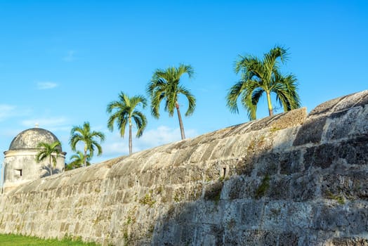 Defensive wall surrounding the historic center of Cartagena, Colombia with palm trees rising above it