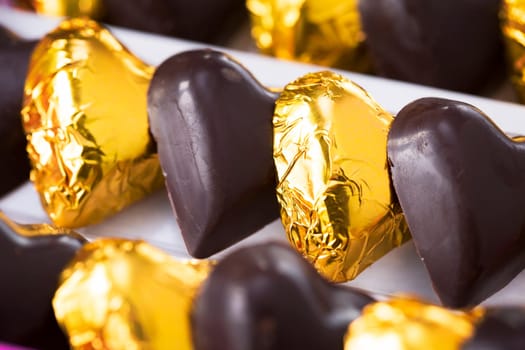 Chocolate hearts, some wrapped in gold foil, close up