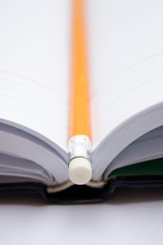 Pencil in a composition with a blank book with hardcovers.