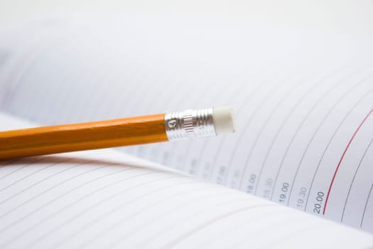 Pencil in a composition with a blank book with hardcovers.