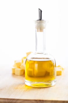 Glass container of oilive oil in front of cubes of butter.