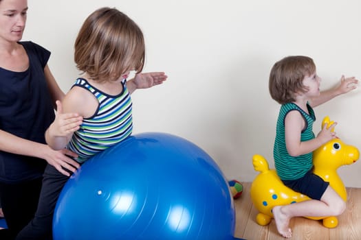Children do gymnastics on a ball, a physical therapist shows exercises for the back
