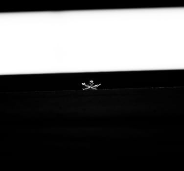 Snowflake falling on a window frame while it's snowing outside.
