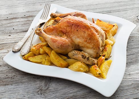 Whole roasted chicken with baked potatoes close up