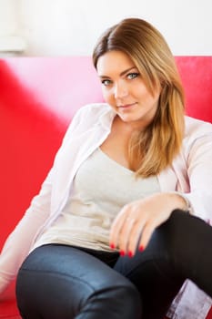 Woman on monotonous red sofa from imitation leather