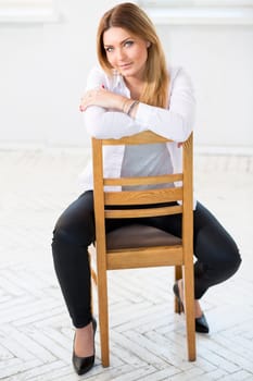 Young woman in white sit backwards on chair