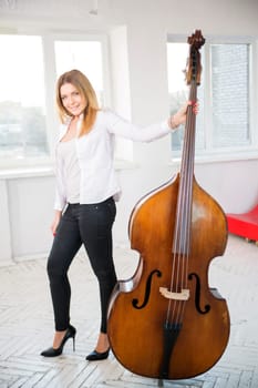 Woman with contrabass at sunny day at studio