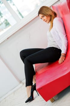 Woman on low red sofa from imitation leather