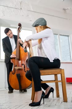 Woman backwards on chair listen man contrabass play