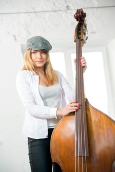 Charming woman and heavy contrabas at white studio