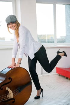 Charming woman rely on big contrabas at studio
