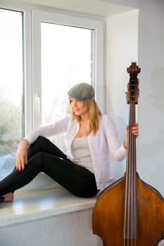 Charming woman with hat hold neck of contrabass