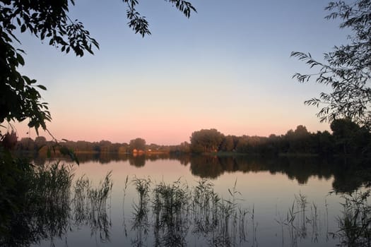 Silent evening and colorful sunset at the lake in summer