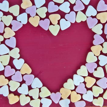 Heart-shaped frame made of colorful candies as background