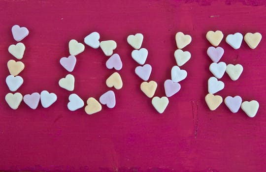 LOVE written with heart-shaped candies on a red background