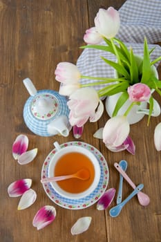 Fresh tea in a colourful cup and tulips in a vase