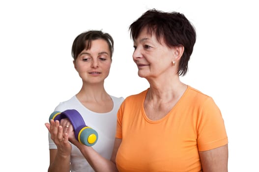 Smiling senior fitness woman exercising with barbells assisted by coach - isolated on white