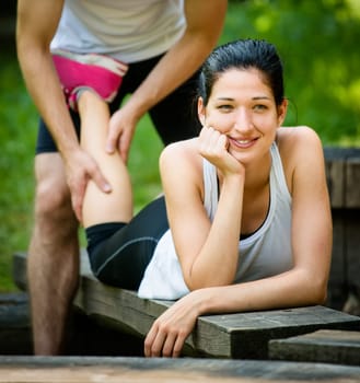Man gives massage of calf to young woman after jogging