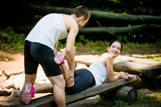 Man gives massage of calf to young woman after jogging