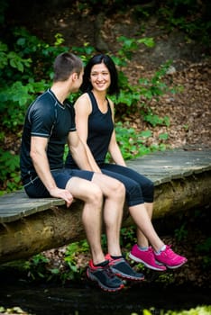 Young sport couple relaxing after sport training on foot bridge in nature