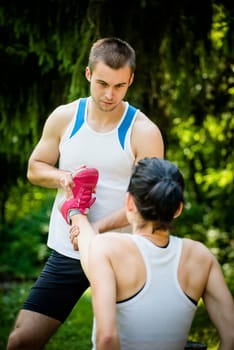 Man helps woman with muscle spasm - stretching her leg