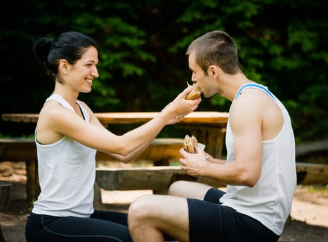 Young sport couple eating after jogging - woman feeding man