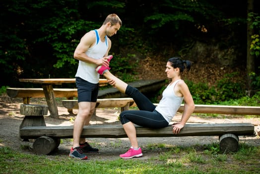 Man stretches womans leg - muscle spasm after sport training