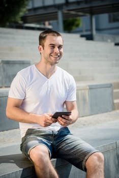 Young smiling man working with tablet - outdoor in town