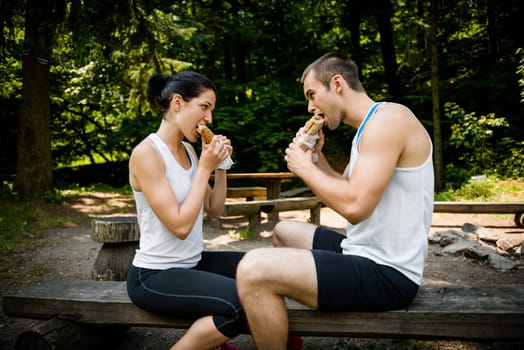Young couple eating together after jogging outdoor in nature
