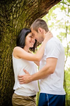 Young couple in love together in nature at tree