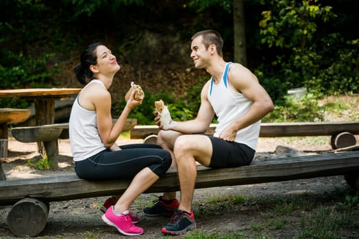 Young couple having fun while eating after sport training outdoor in nature