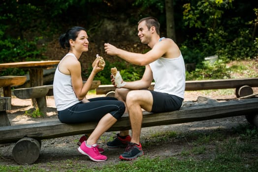 Young couple having fun while eating after sport training outdoor in nature